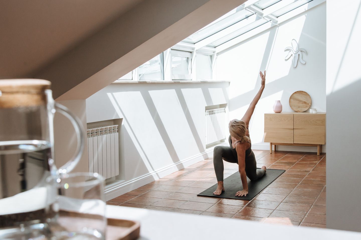A woman performs yoga in a sunlit room with elegant decor, promoting relaxation and mindfulness.
