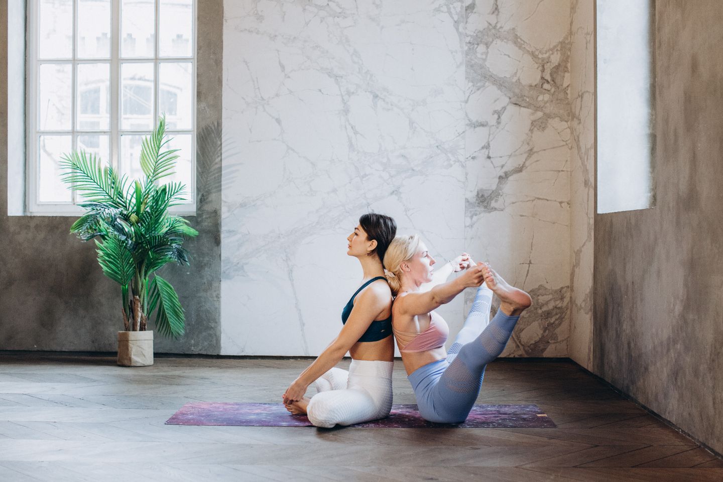 Two women engaged in yoga practice indoors, promoting mindfulness and wellness.
