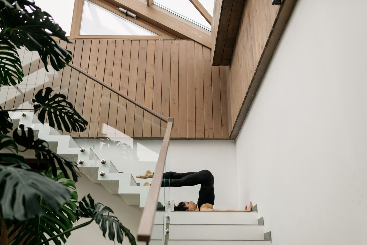 Woman performing yoga stretch on staircase, blending fitness and architecture.